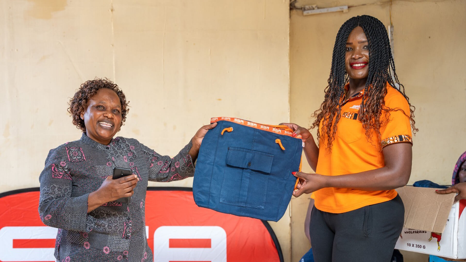 Two people posing while holding a bag